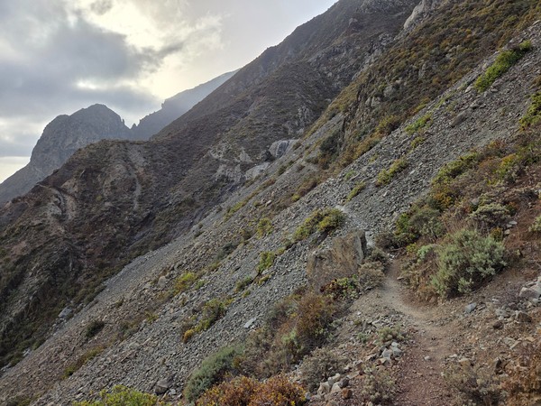Schmaler Bergpfad führt durch einen steilen, felsigen Hang in den Anaga-Bergen unter dramatischem Himmel.