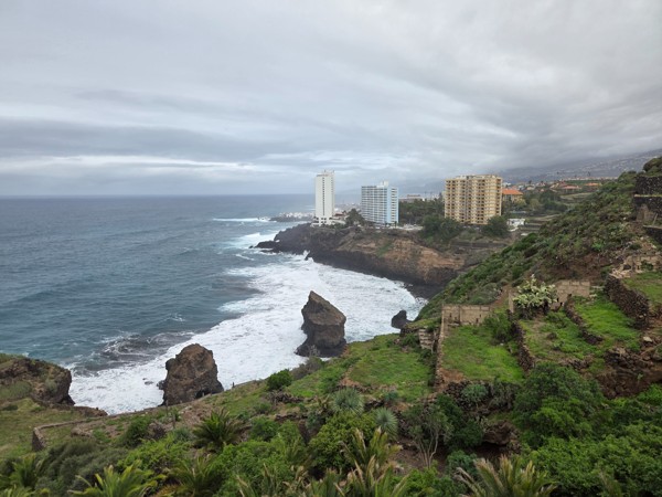 Küstenlandschaft am Mirador de los Roques mit hohen Wellen, steilen Felsen, grünen Terrassen und dramatischem Himmel.
