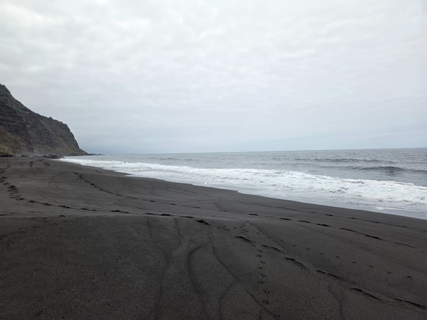 Leerer schwarzer Strand von La Garañona mit grauem Himmel, sanfter Brandung und wilder Küstenstimmung.