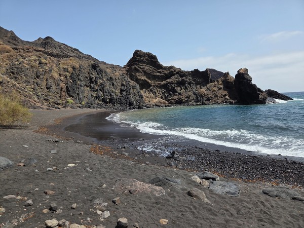 Abgelegene Bucht von Roque Bermejo mit schwarzem Sand, dunklen Vulkanfelsen und klarem Wasser.