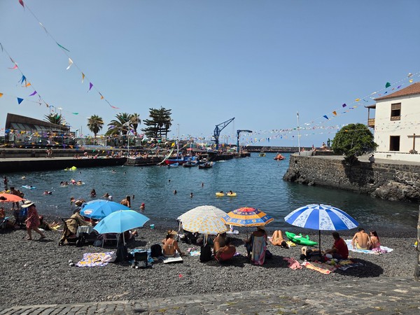 Viele Menschen genießen das Wasser und den Strandbereich am Hafen von Puerto de la Cruz an einem sonnigen Feiertag.