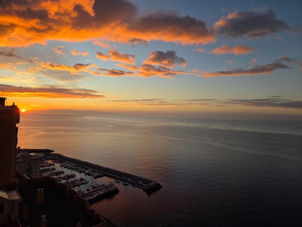 Sonnenaufgang über dem Meer bei Radazul mit orangefarbenen Wolken und ruhigem Wasser über dem Hafen.