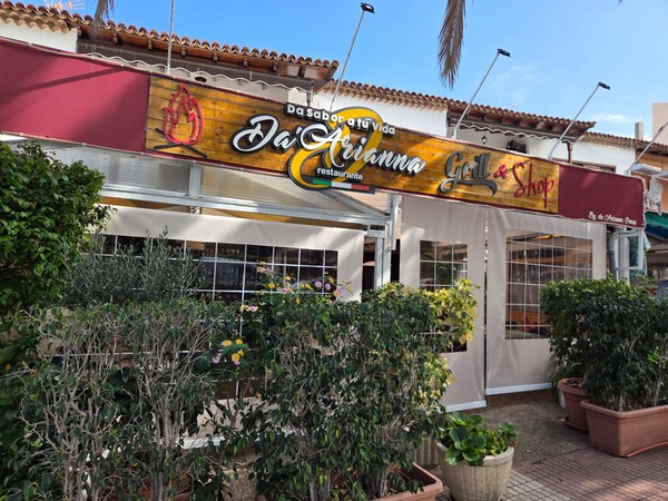 Frontansicht des Restaurants Da Arianna Grill & Shop mit Holzschild, Pflanzen und überdachter Terrasse.