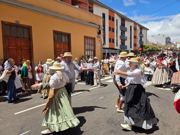 Traditionell gekleidete Tänzer und Musiker ziehen bei der Romería de San Benito Abad durch eine festlich geschmückte Straße.
