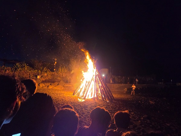 Großes Johannisfeuer am Strand von Puerto de la Cruz bei Nacht, umgeben von Zuschauern und fliegenden Funken.