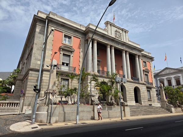 Historisches Regierungsgebäude in Santa Cruz de Tenerife mit Säulenfassade, Flaggen und breiter Treppe an einer Straße.