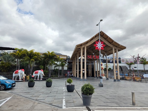 Eingang des Siam Mall auf Teneriffa mit markantem Dach, tropischen Pflanzen und dekorativen Elefanten vor dem Gebäude.